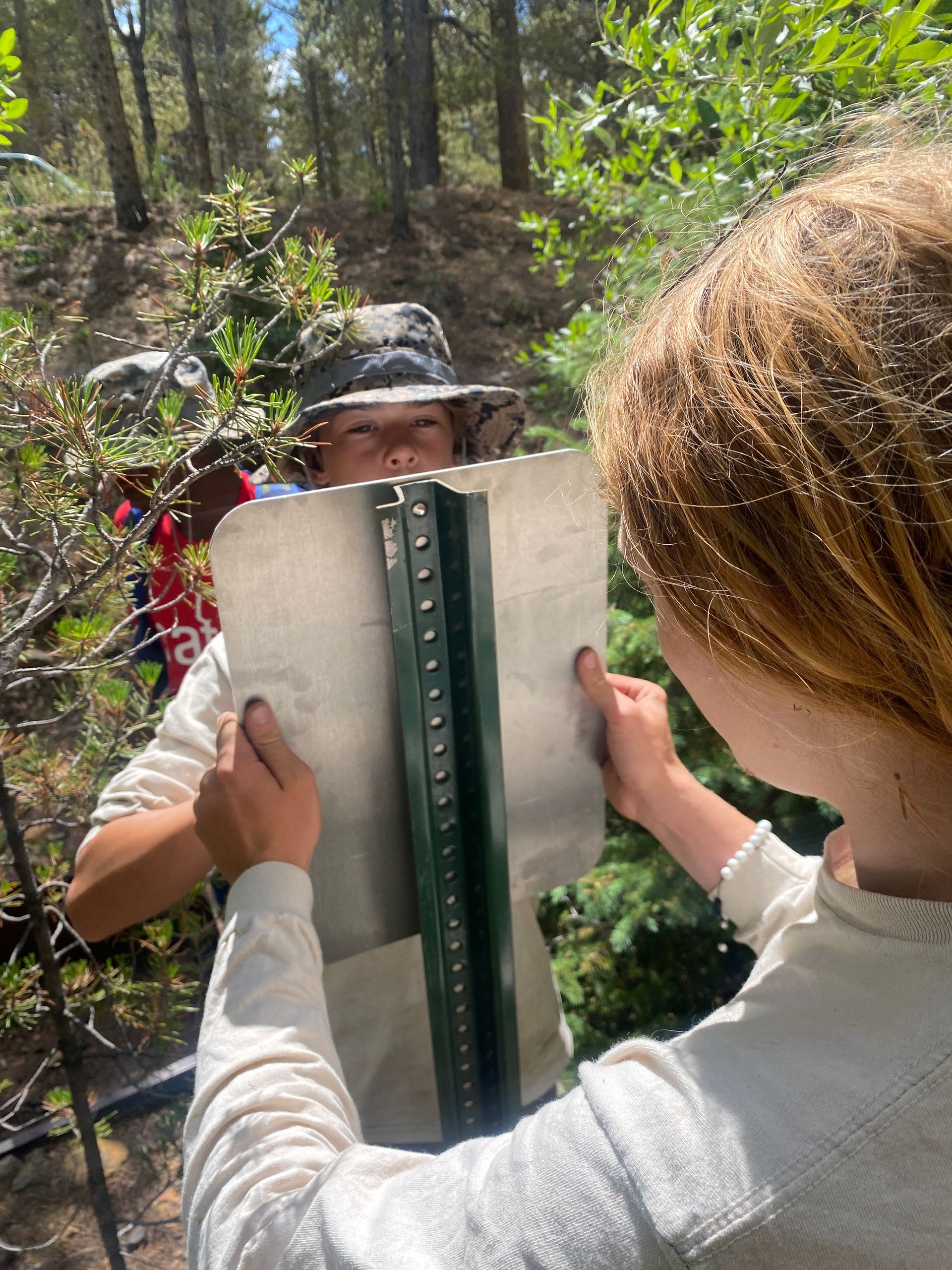 A man and a woman are holding a metal pole in the woods.