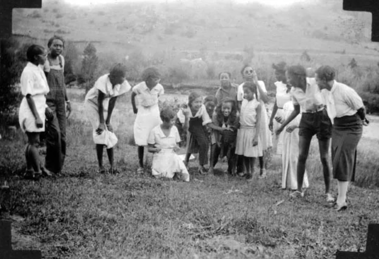 A black and white photo of a group of people standing in a field.