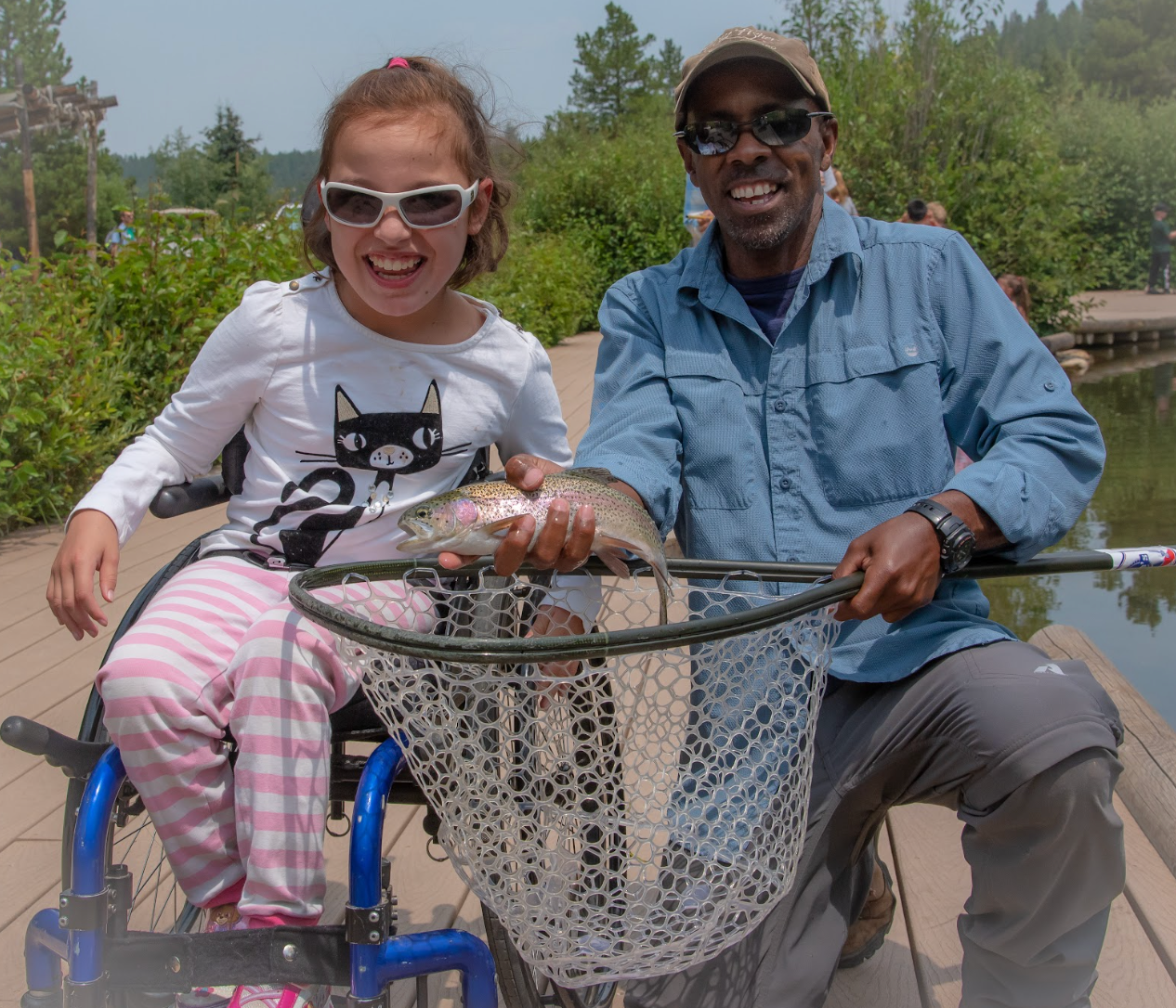 A man and a little girl are holding a fish in a net