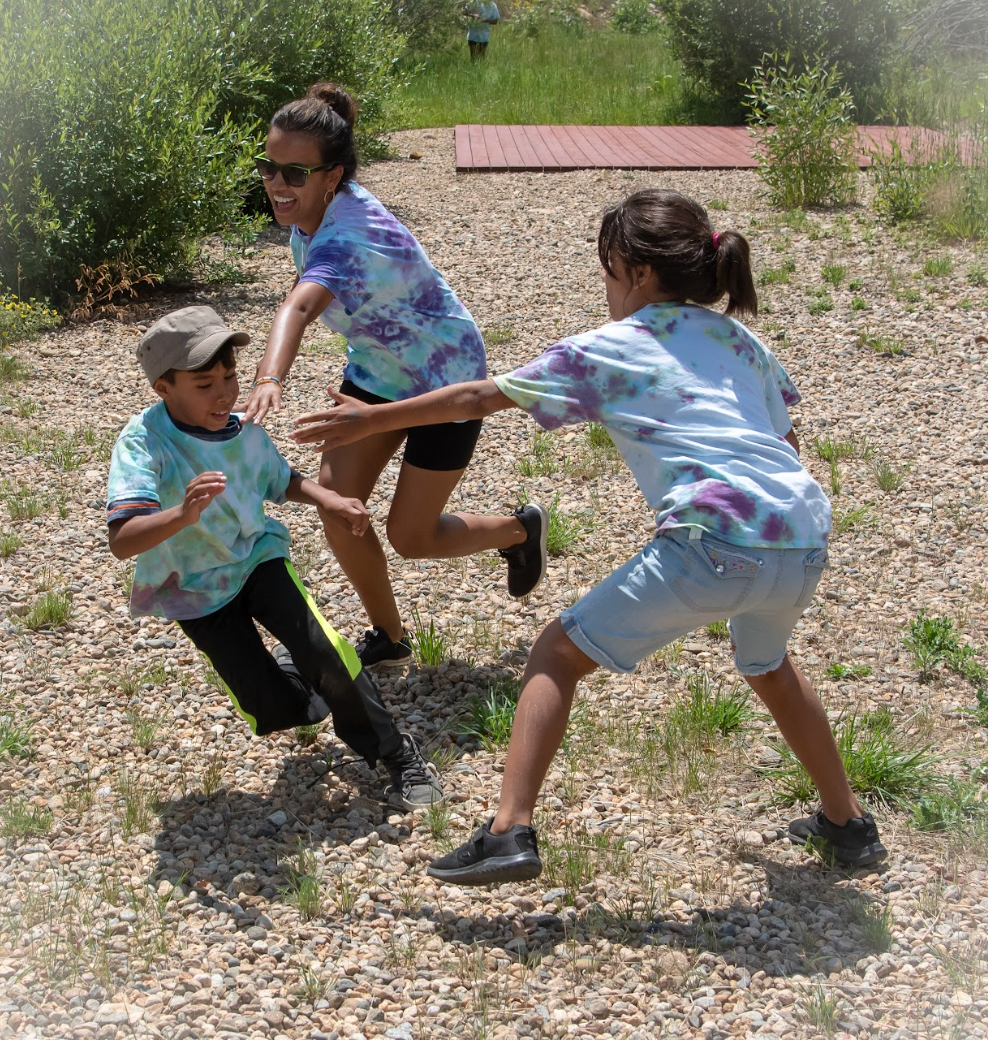 A woman and two children are playing a game of frisbee