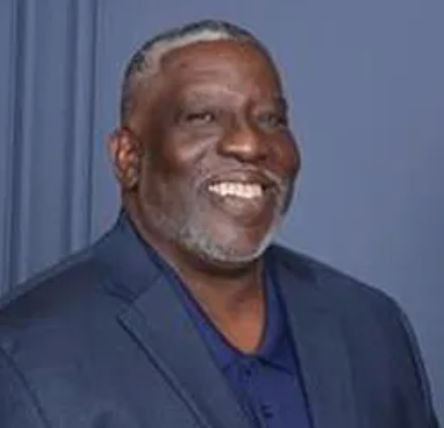 A man in a suit and blue shirt is smiling for the camera.