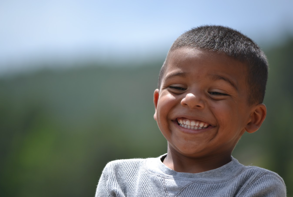 A young boy is smiling with his eyes closed.