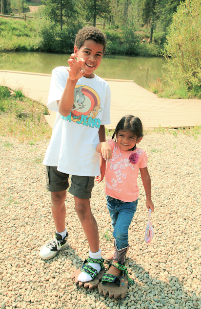 A boy and a girl are standing next to each other in front of a lake.