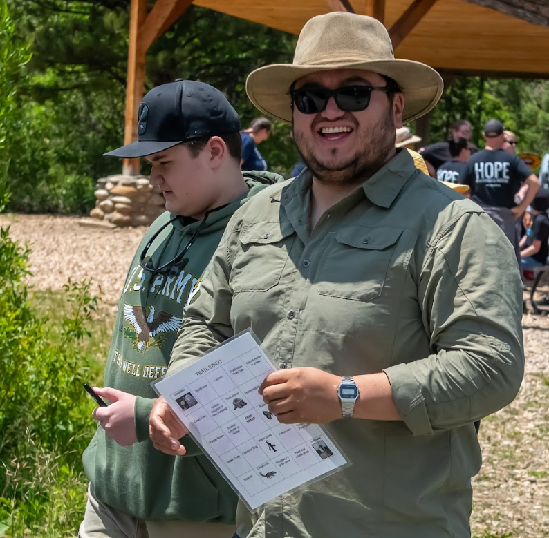 A man wearing a hat and sunglasses is holding a piece of paper