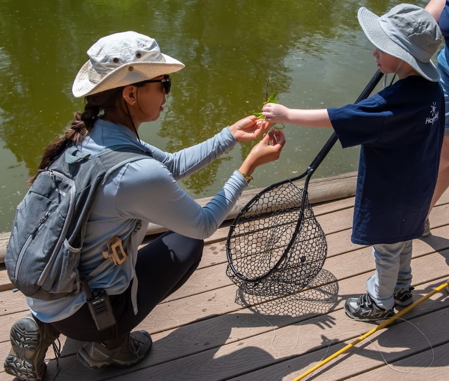 A woman is kneeling down next to a child holding a fishing net.