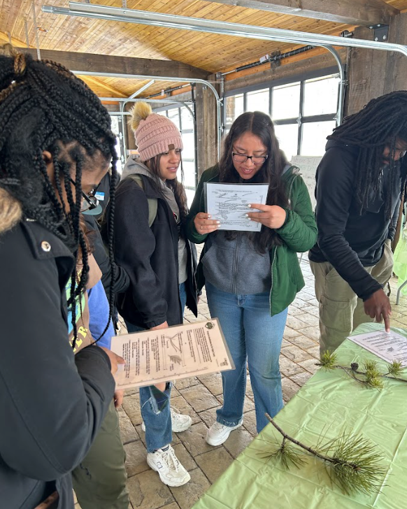 A group of people are standing around a table looking at a sign.