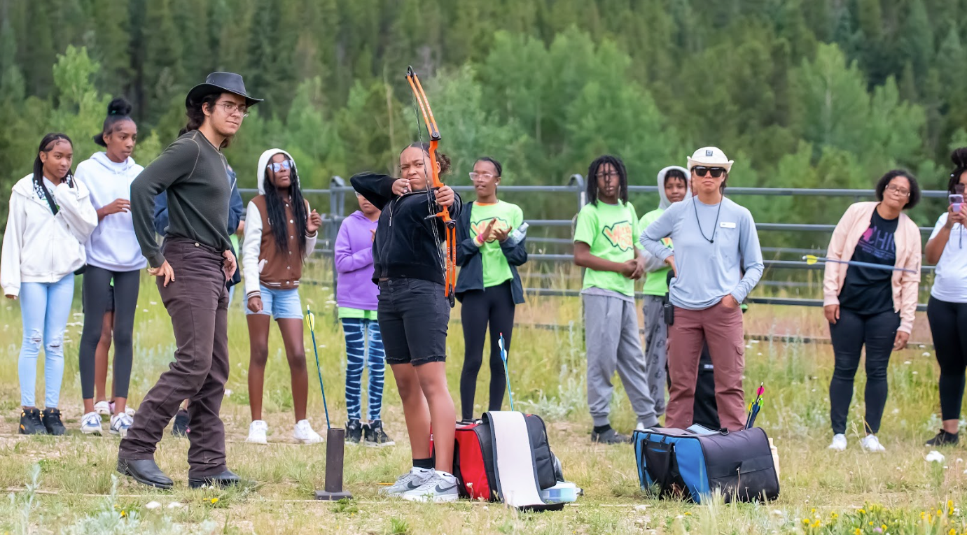 A group of people are standing in a field holding bows and arrows.