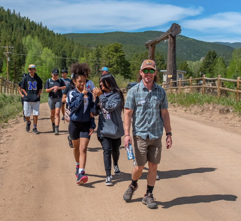 A group of people are walking down a dirt road.