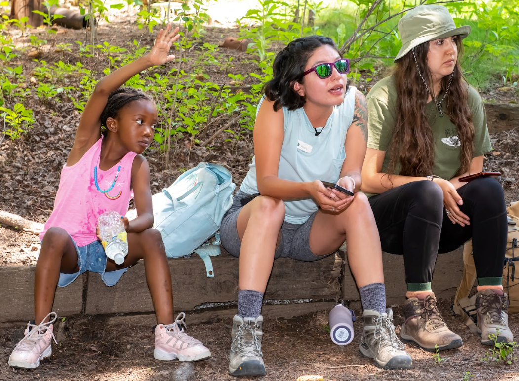 Three women and a little girl are sitting on a bench.