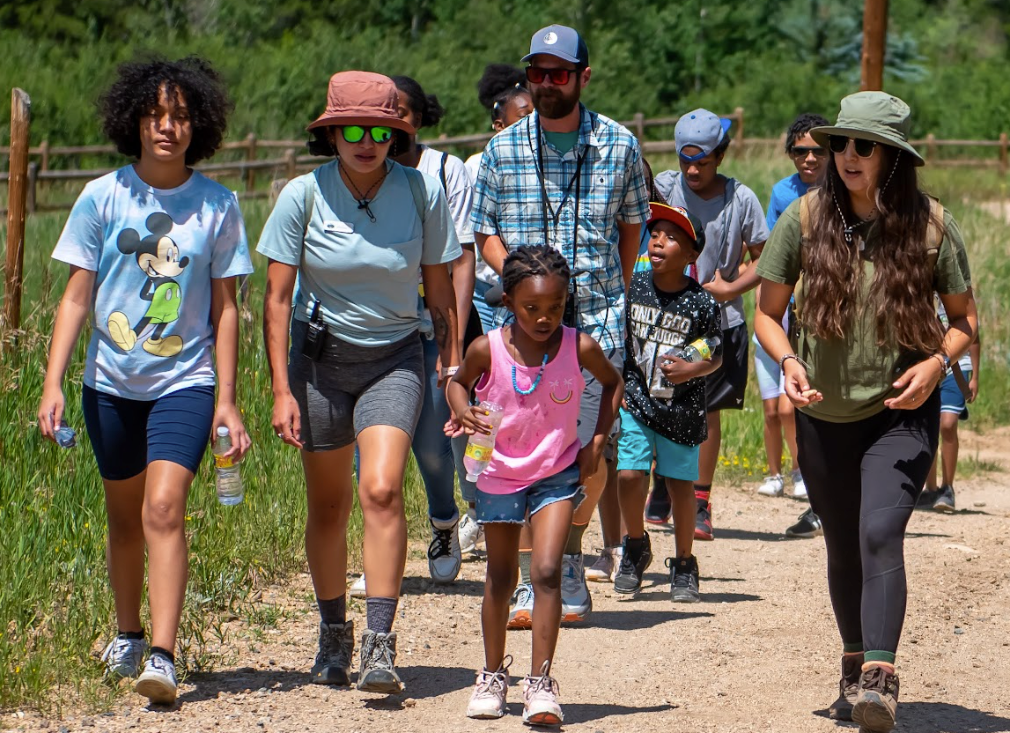 A group of people are walking down a dirt path.