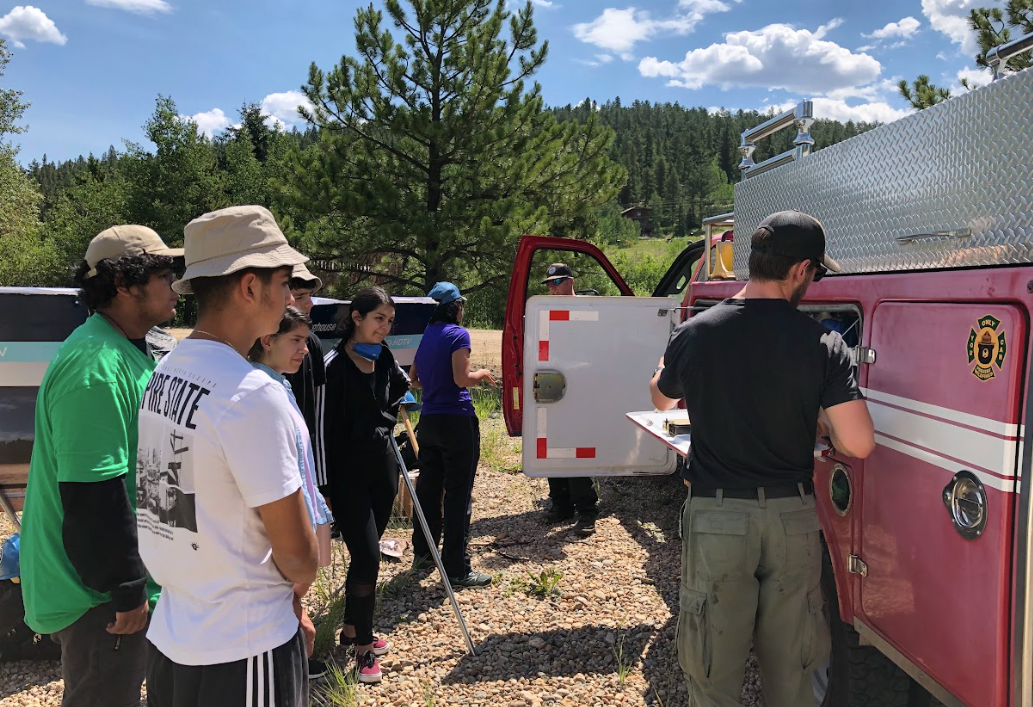 A group of people are standing in front of a pink fire truck.
