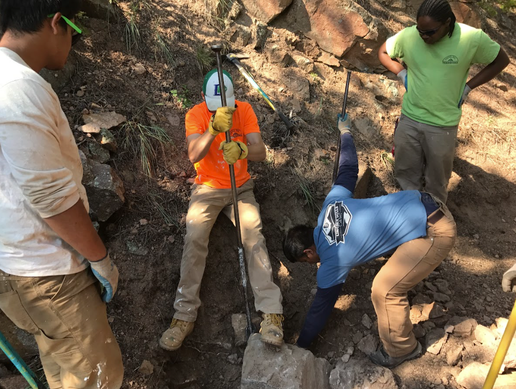 A group of men are working on a rocky hillside.