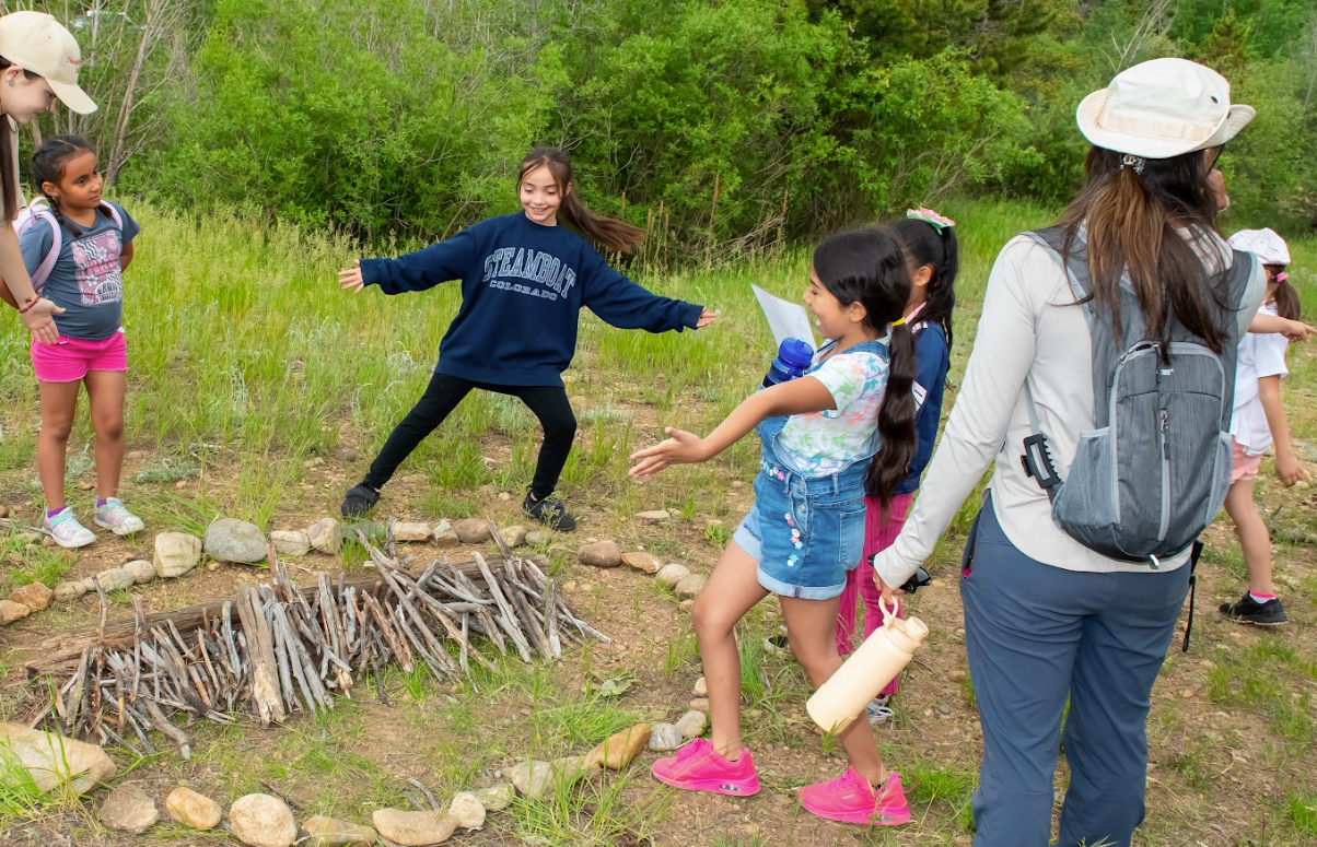 A group of children are playing in a circle in the woods.