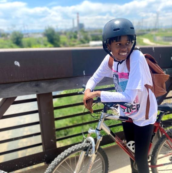 A young girl wearing a helmet is riding a bike on a bridge