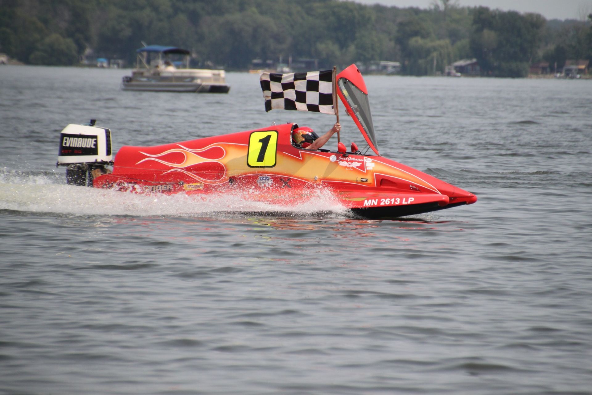 A red and yellow boat with the number 1 on it is racing on a lake.