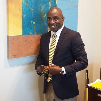 A man in a suit and tie is standing in front of a painting.