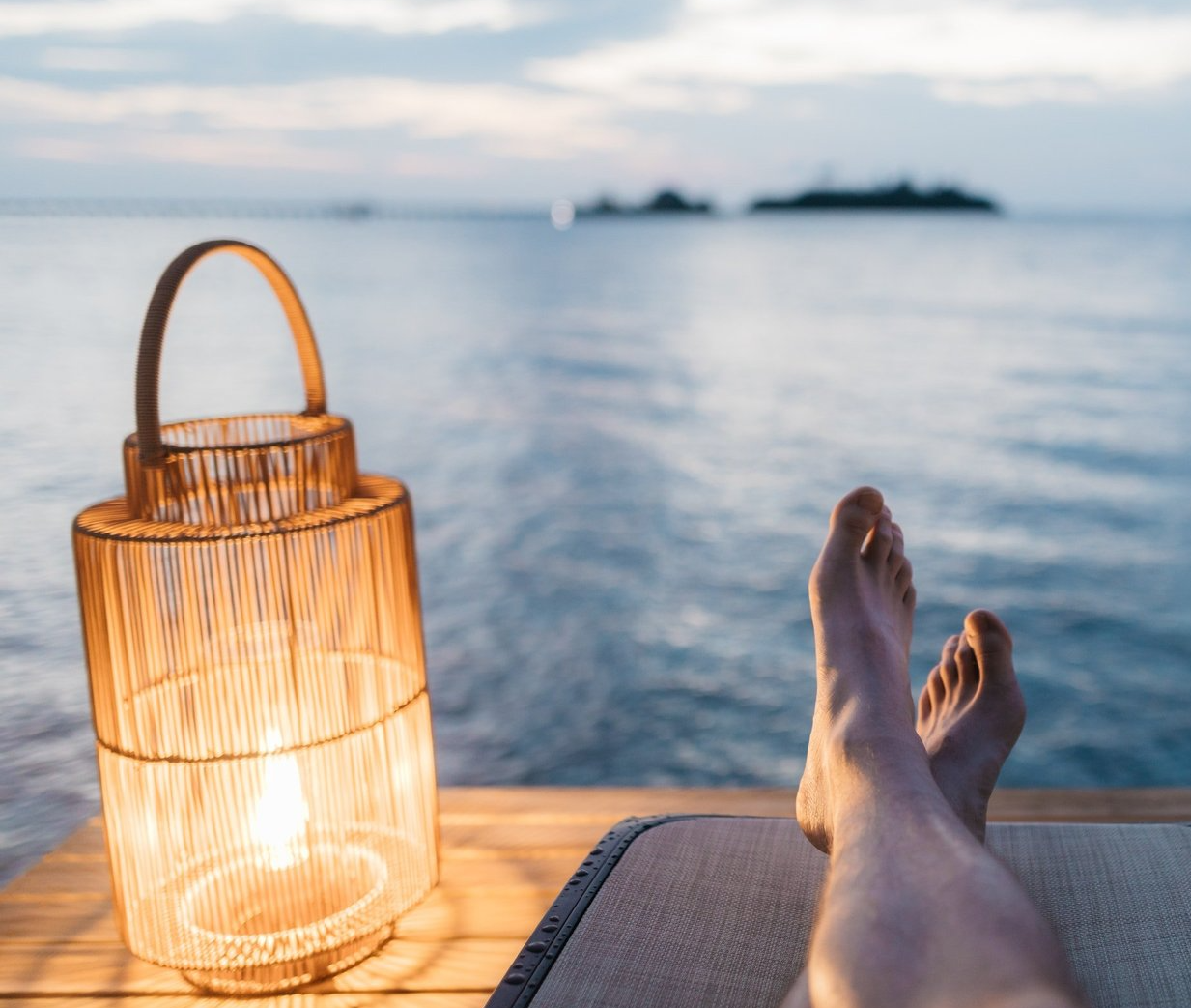Een persoon ligt op een steiger met zijn voeten omhoog voor de oceaan.