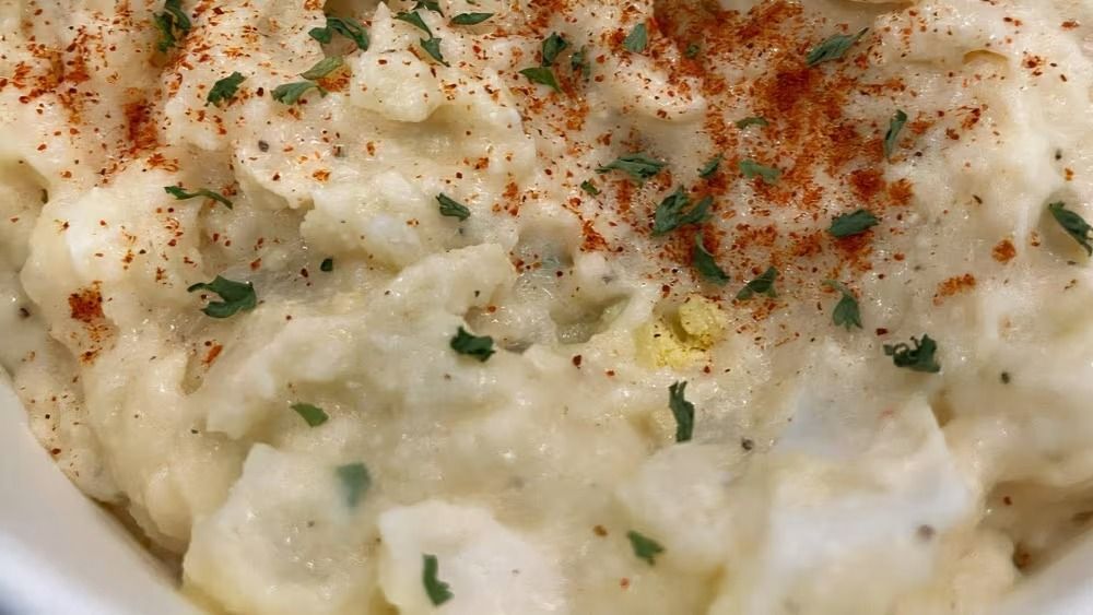 Creamy potato salad topped with paprika and parsley.