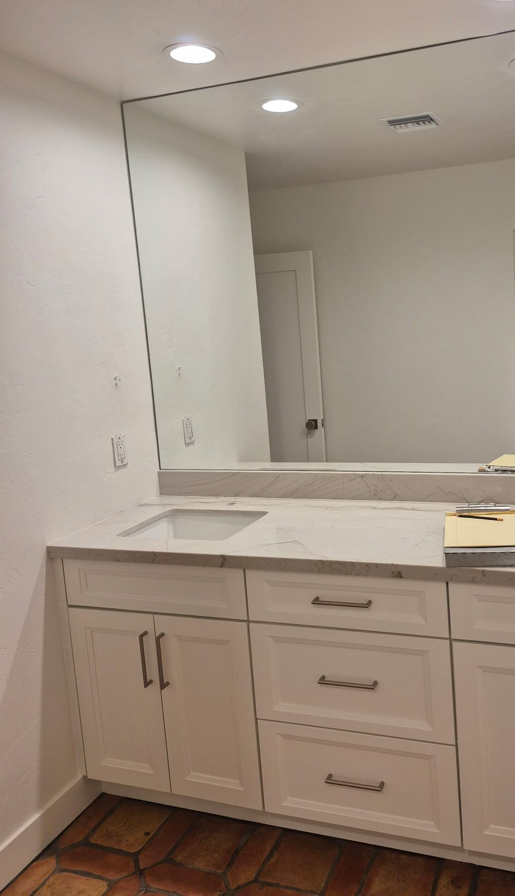 Bathroom with white vanity, large mirror, and recessed lighting.