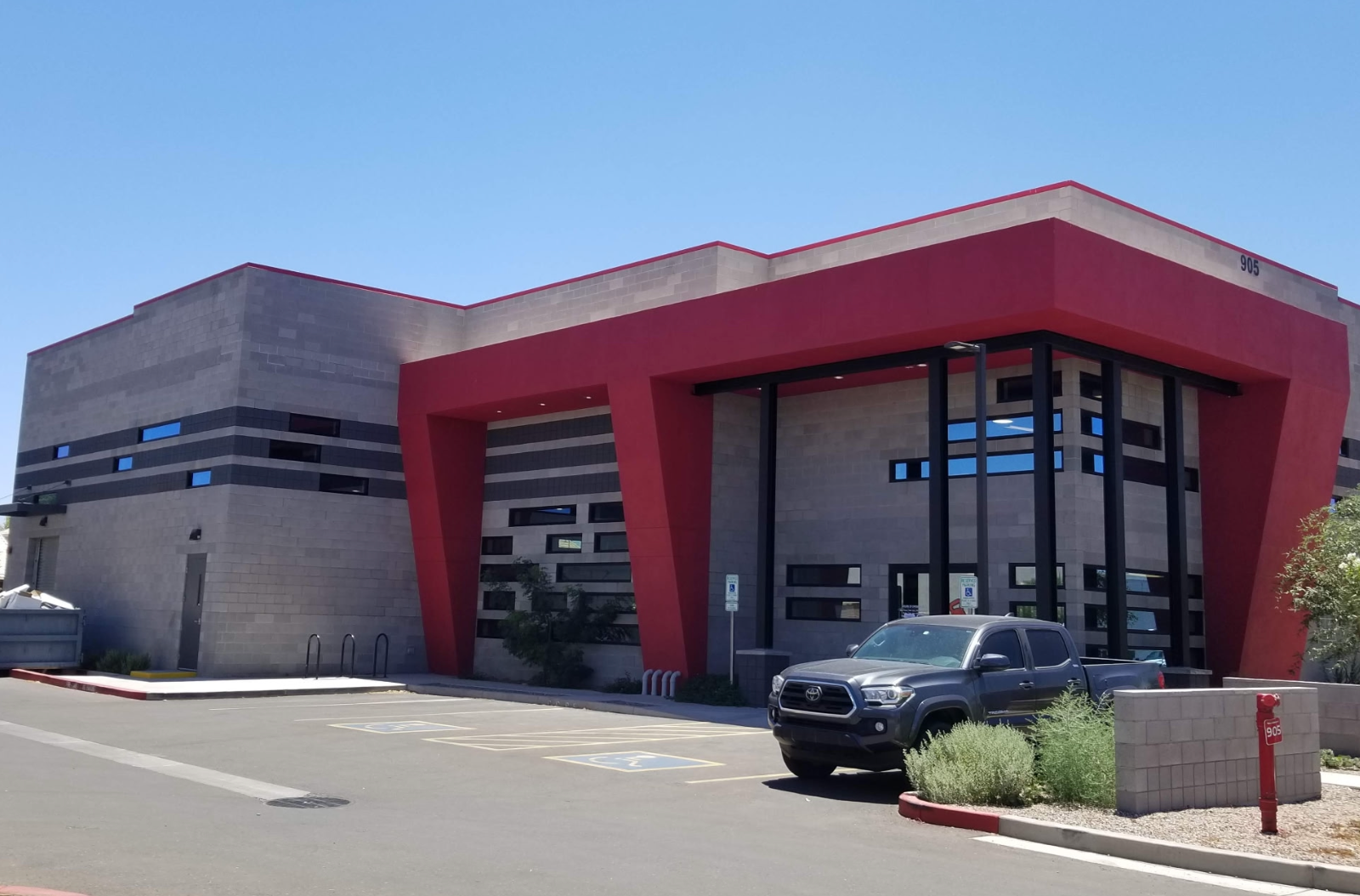 Restaurant exterior with large windows, tables, and lush greenery.