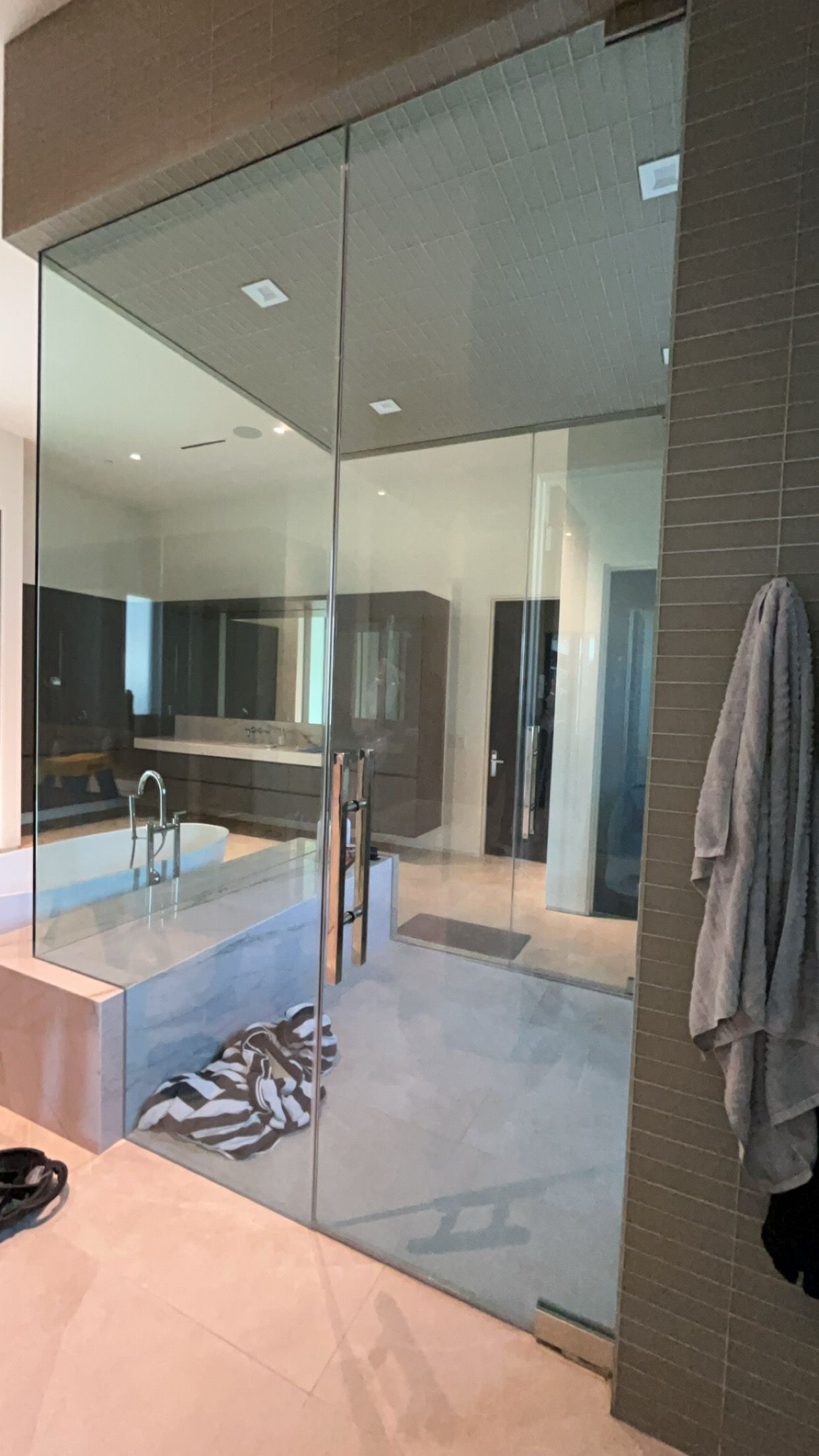 Glass shower door in a modern bathroom, towel hanging on the right.