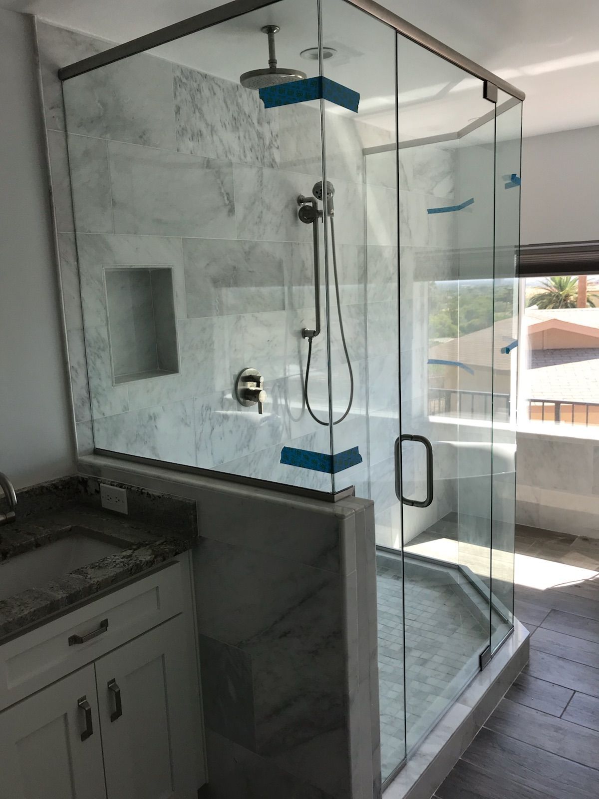 Glass shower enclosure with marble tiles and a built-in niche.