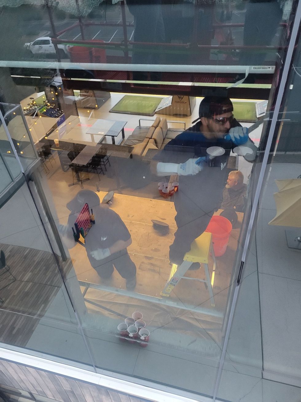 People gathered around a bright indoor display seen through a glass floor/ceiling.