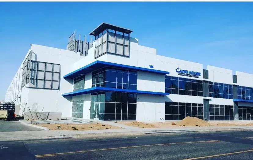 White modern building with blue accents, large windows, and a blue sky.