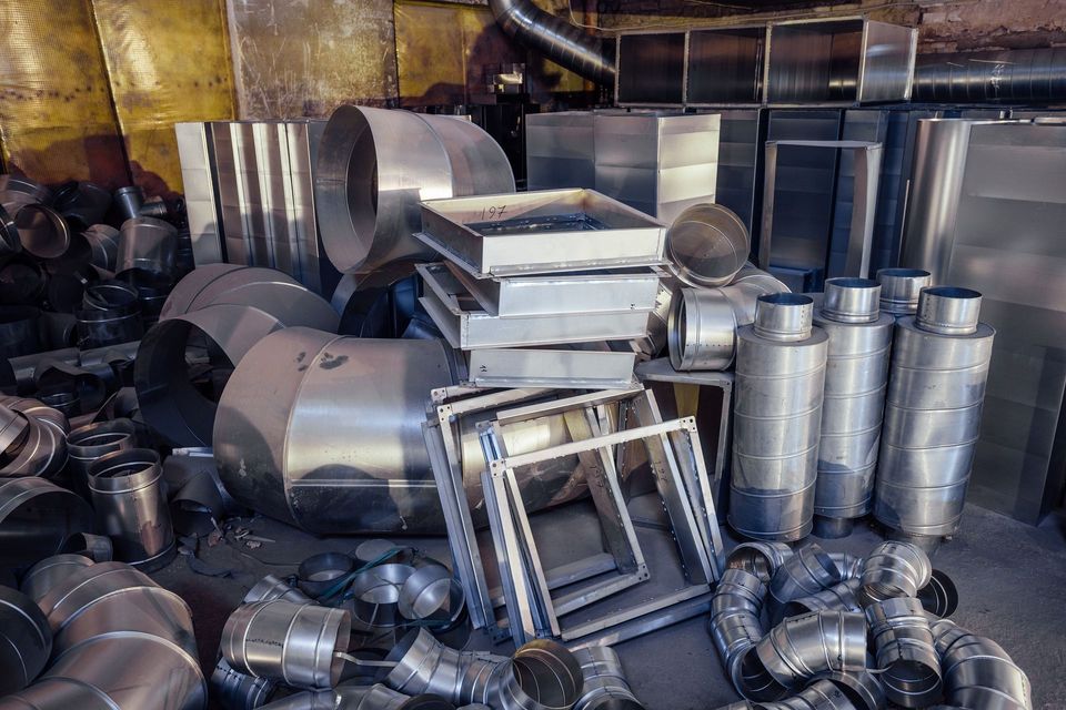 A pile of stainless steel pipes and ducts in a factory.