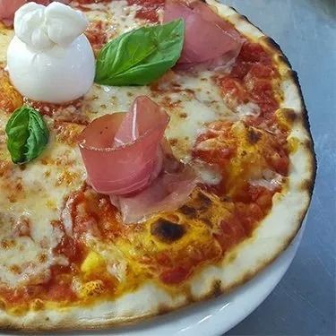 Postazione di lavoro del barbiere con tagliacapelli, forbici, spazzole, oli e uno specchio che riflette una sedia sfocata.