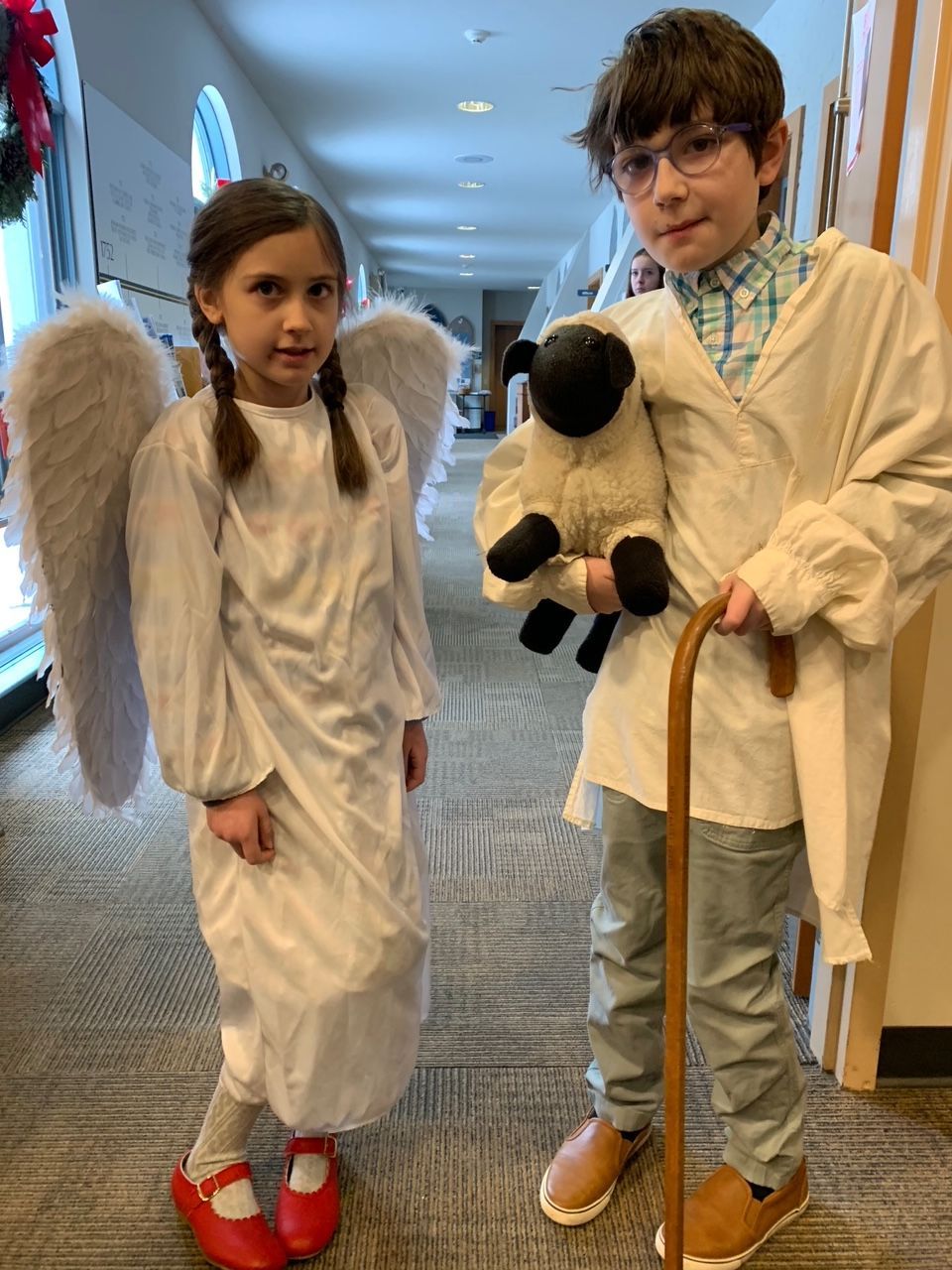 A girl dressed as an angel and a boy dressed as a shepherd holding a stuffed sheep