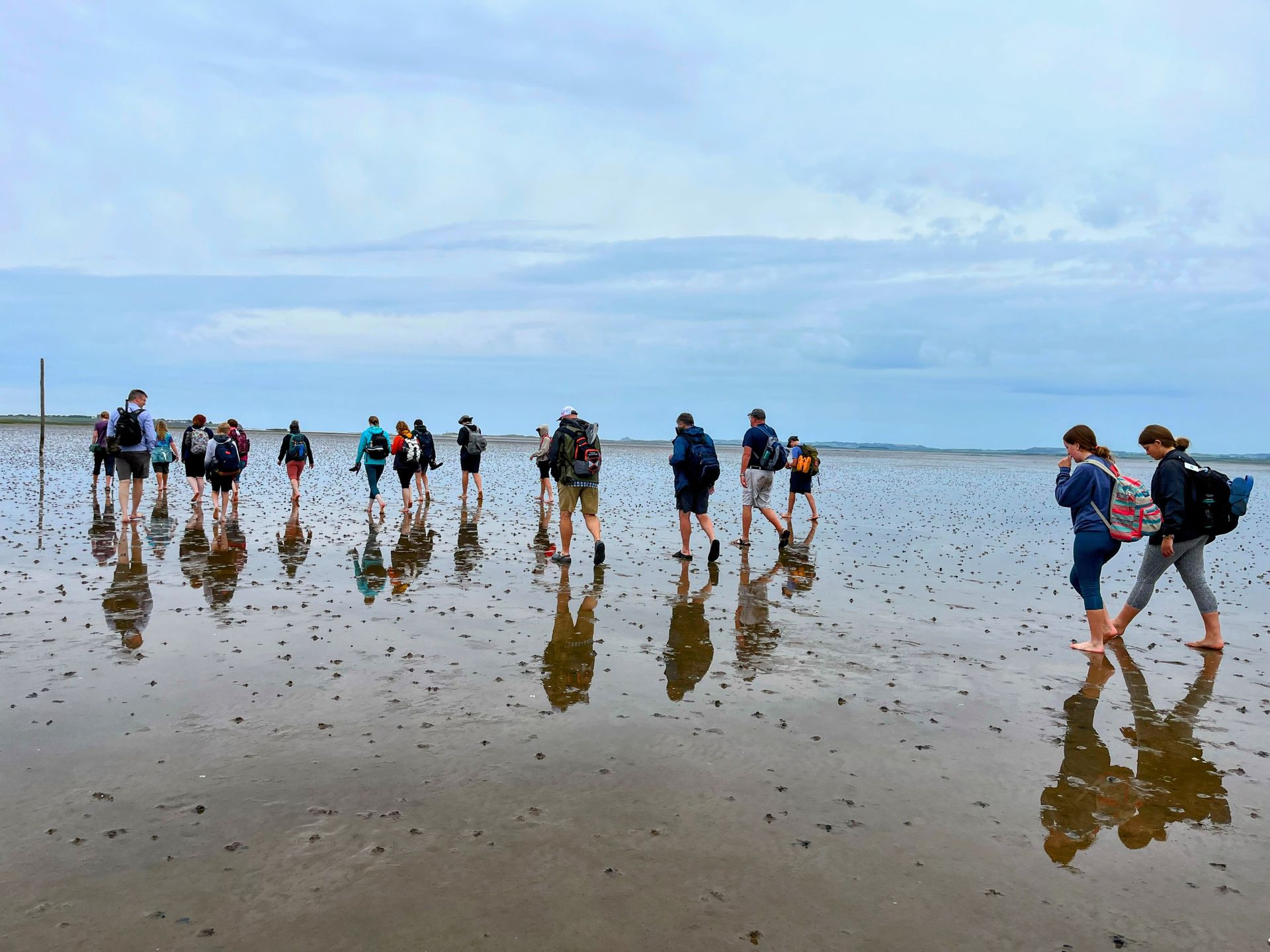 A group of people walking barefoot on a beach