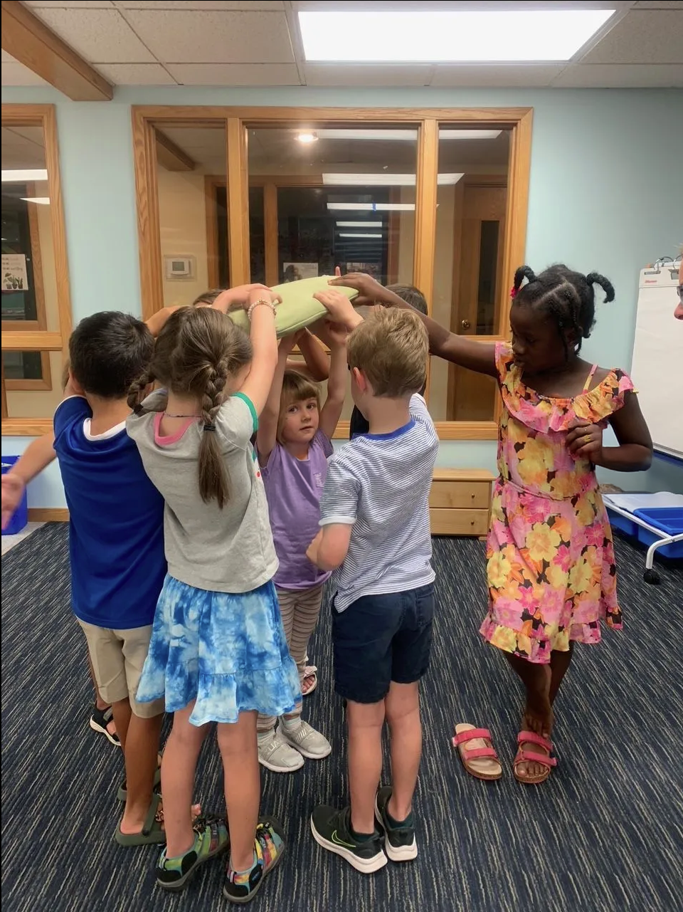 A group of children are standing in a circle with their hands in the air