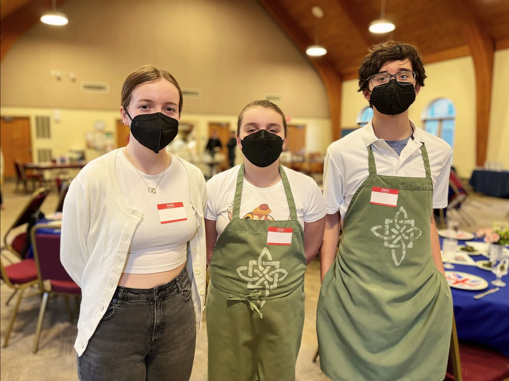 Three people wearing face masks and aprons pose for a picture