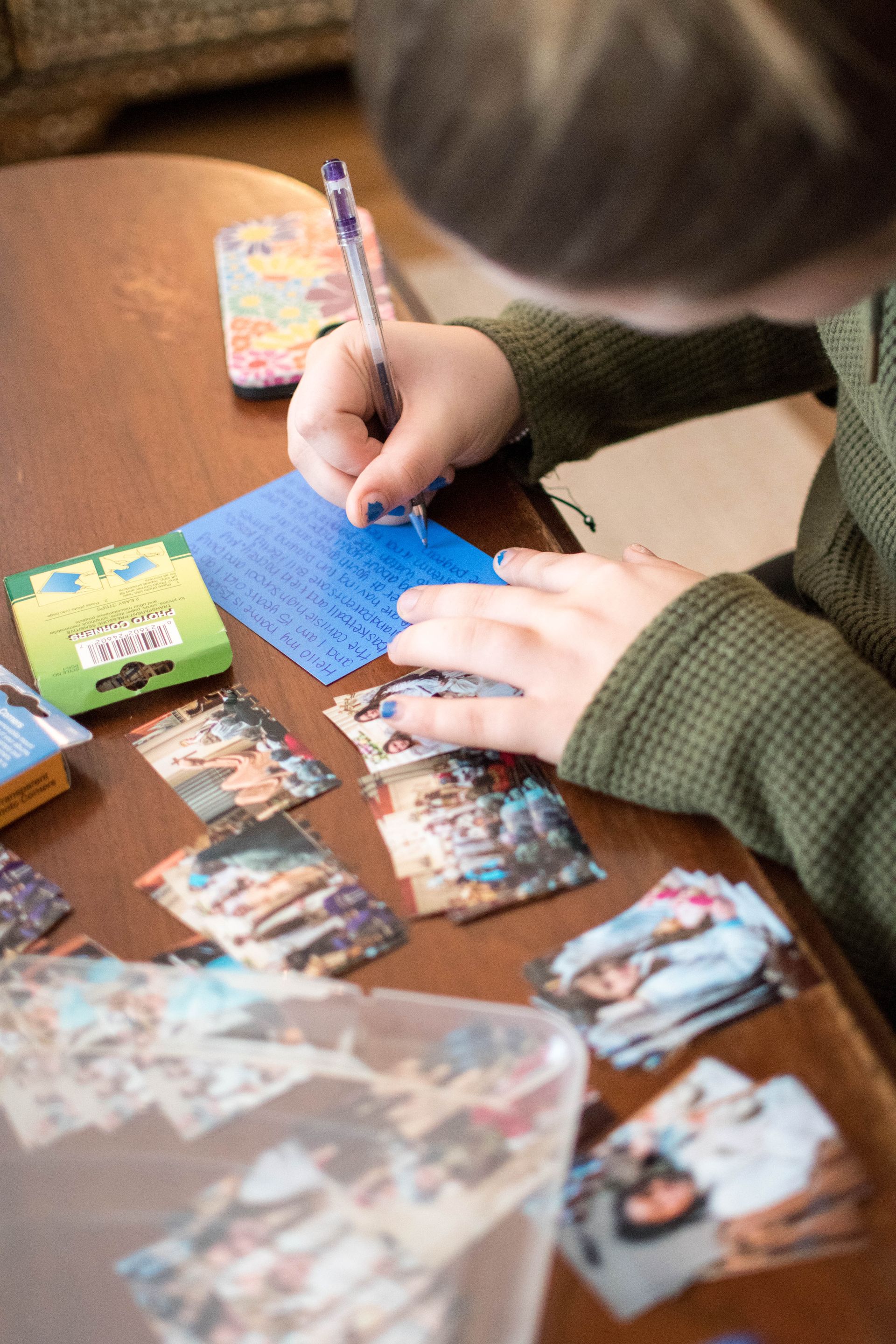 A child is writing on a piece of paper with a pen