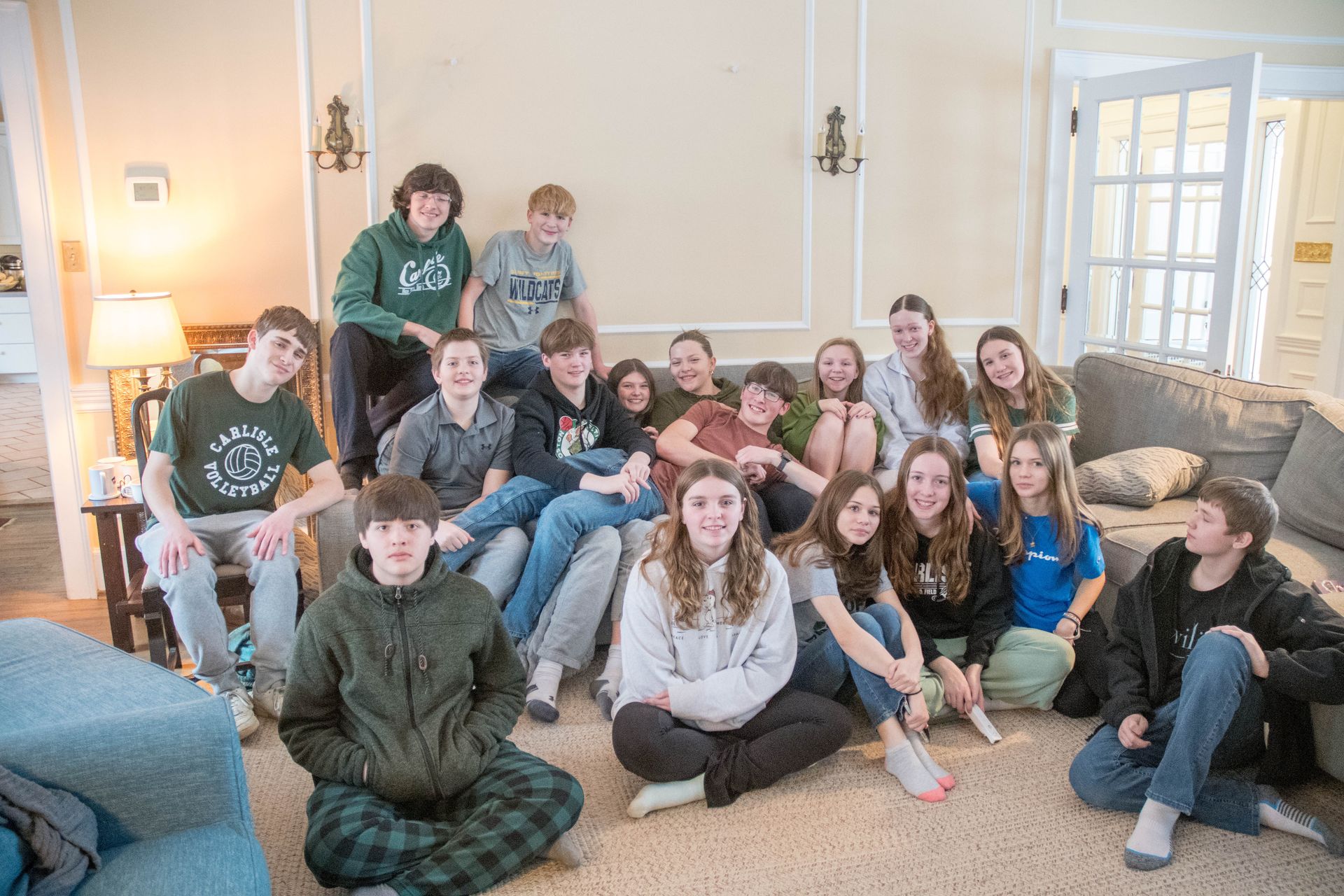 A group of young people are sitting on the floor in a living room