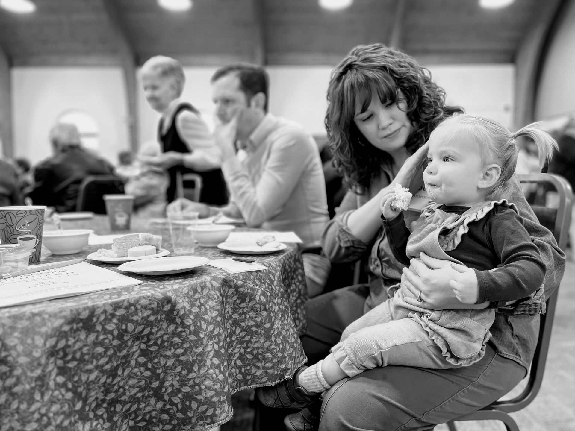 A woman is holding a baby while sitting at a table.