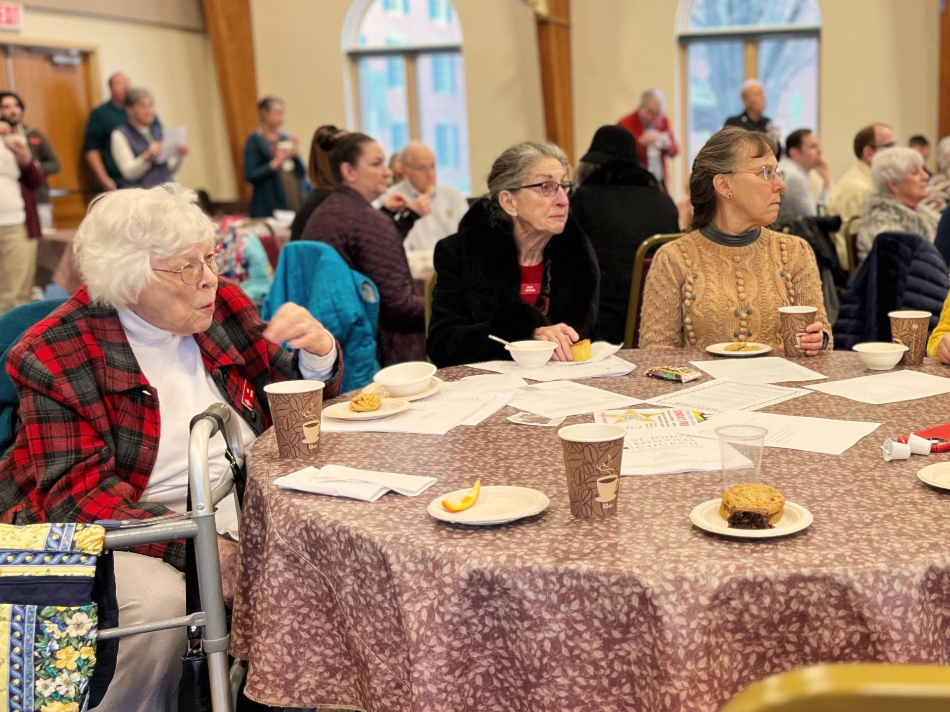 A woman in a wheelchair sits at a table with other people