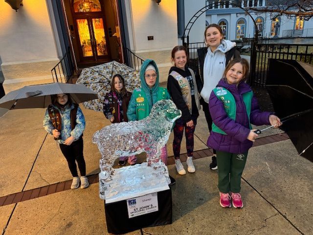 A group of young girls standing around a statue of a sheep
