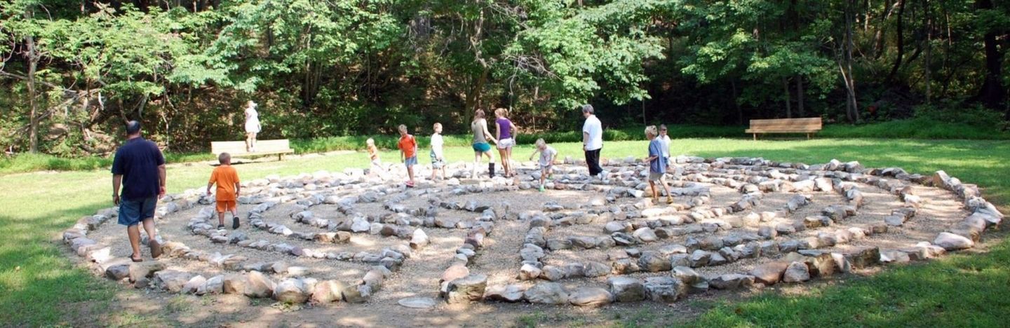 A group of people are standing around a large rock labyrinth