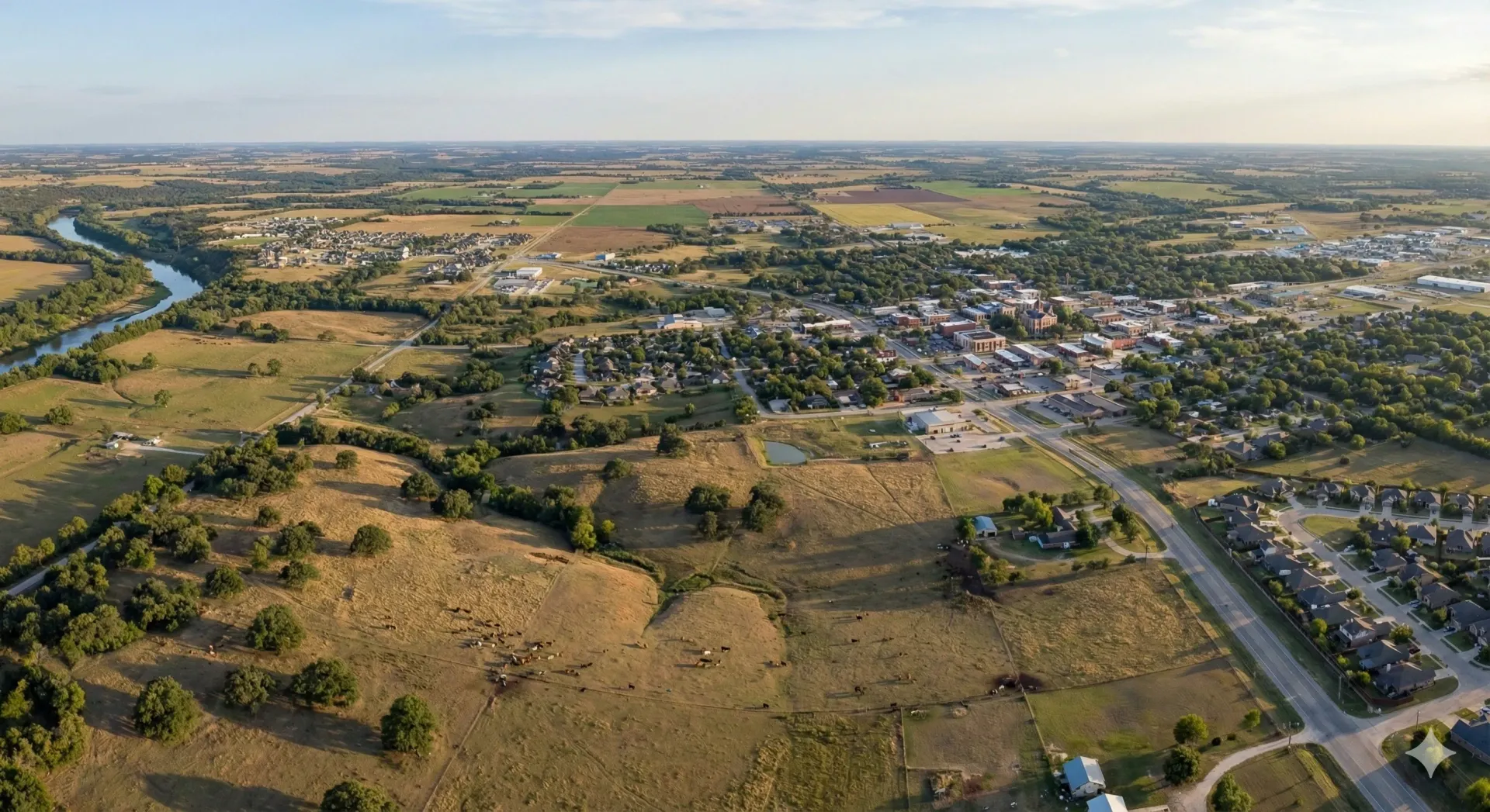 An aerial view of a river surrounded by trees and grass