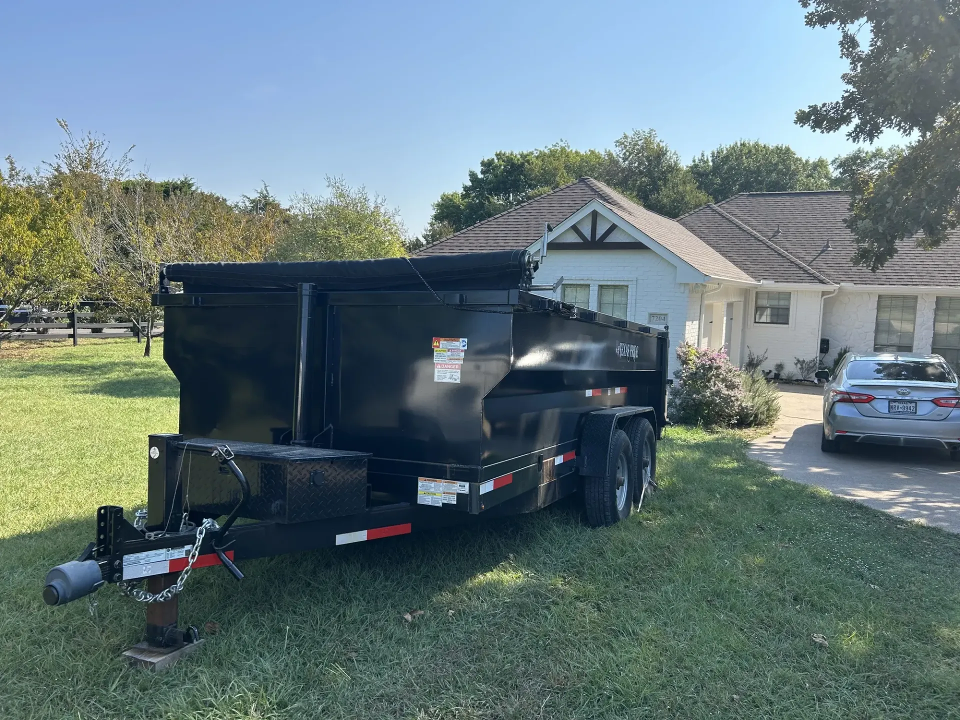A dumpster is parked in the snow in front of a house.
