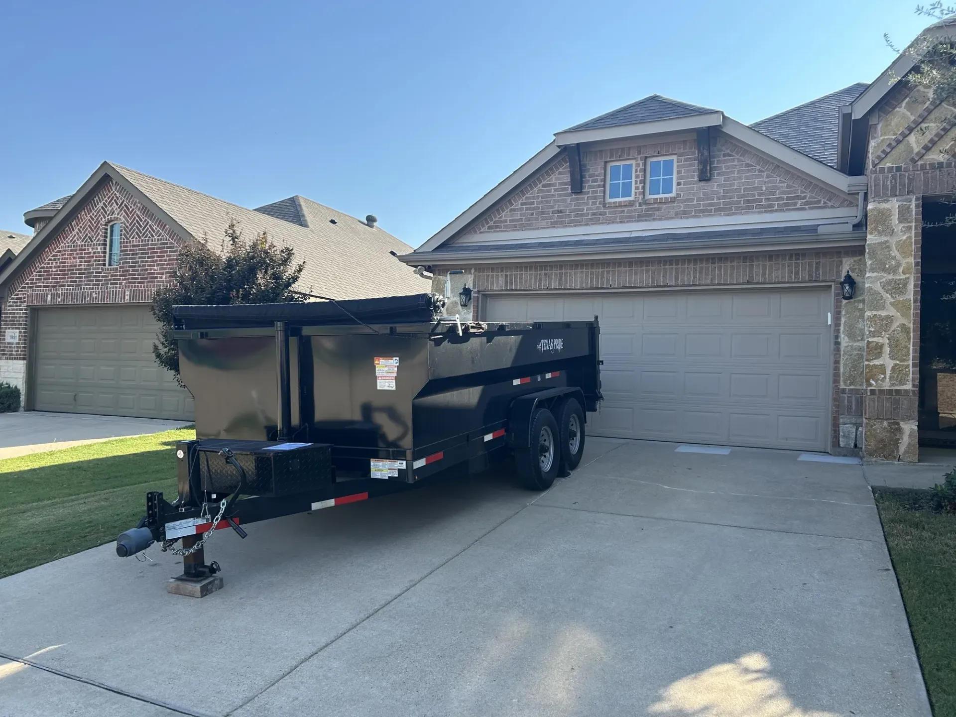 A green dumpster is parked in front of a house.