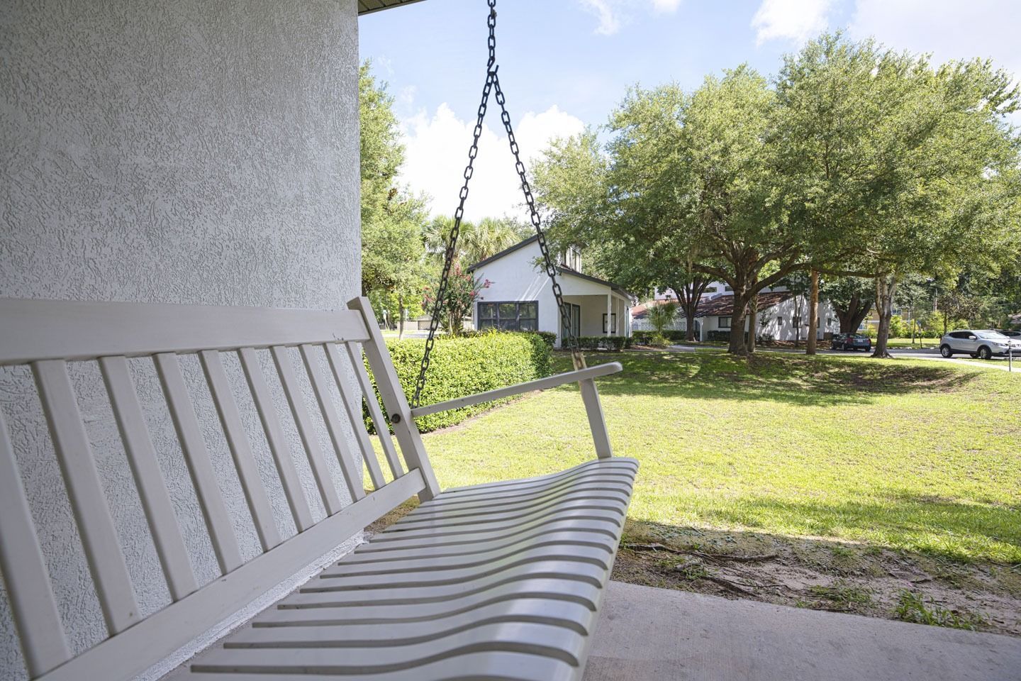 A porch swing is hanging from the side of a house.