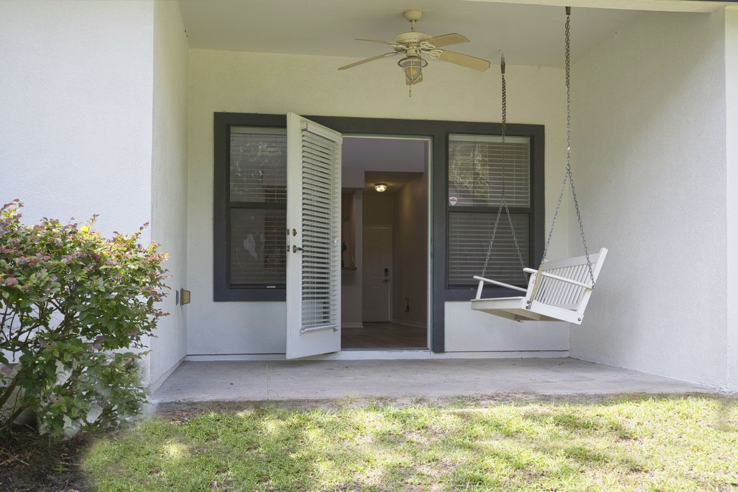 A porch with a swing and a ceiling fan.