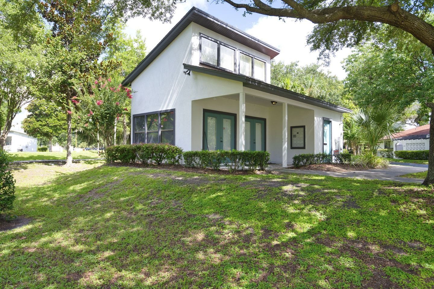 A white house with a black roof is sitting on top of a lush green lawn.
