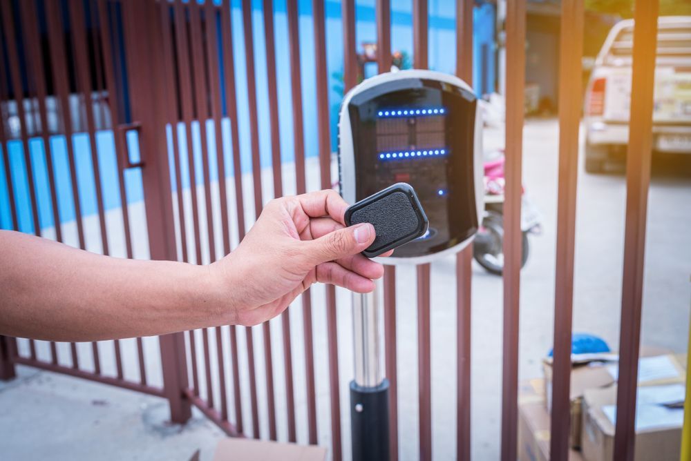 Hand Holding Remote Near a Gate Access Control Panel — Industry Fire Services in Bowen, QLD