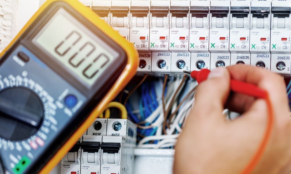 Electrician Using a Multimeter to Check the Voltage in a Circuit Breaker Panel — Industry Fire Services in Bowen, QLD