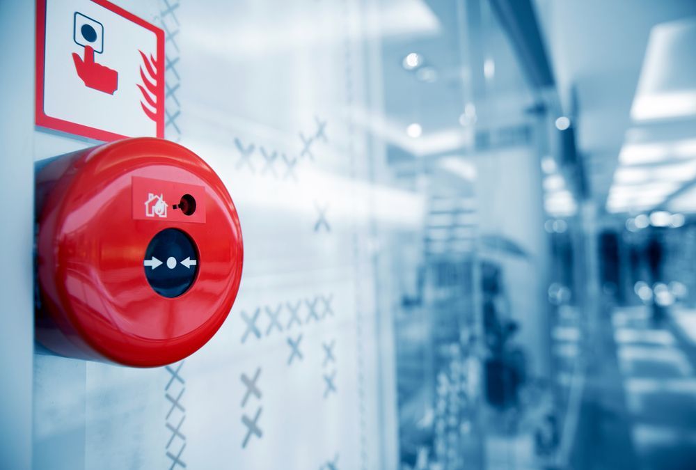 Red Fire Alarm With Sign, Mounted on a White Wall in a Public Building — Industry Fire Services in Mount Isa, QLD