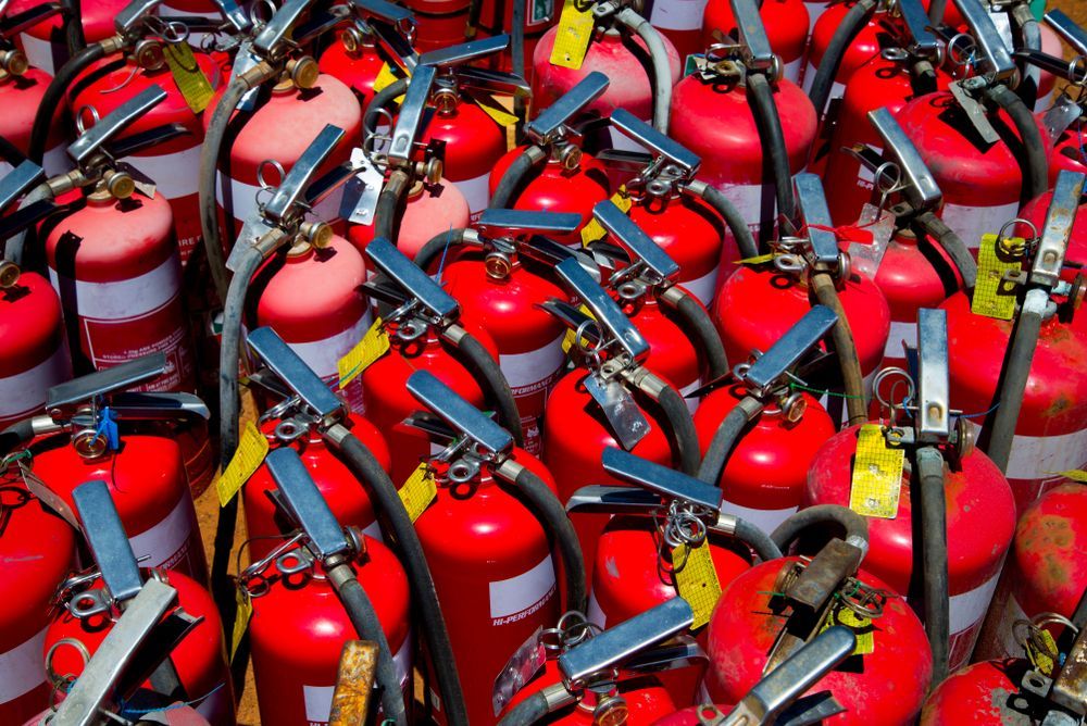 A Group of Red Fire Extinguishers With White Bands, Arranged Closely Together — Industry Fire Services in Bowen, QLD